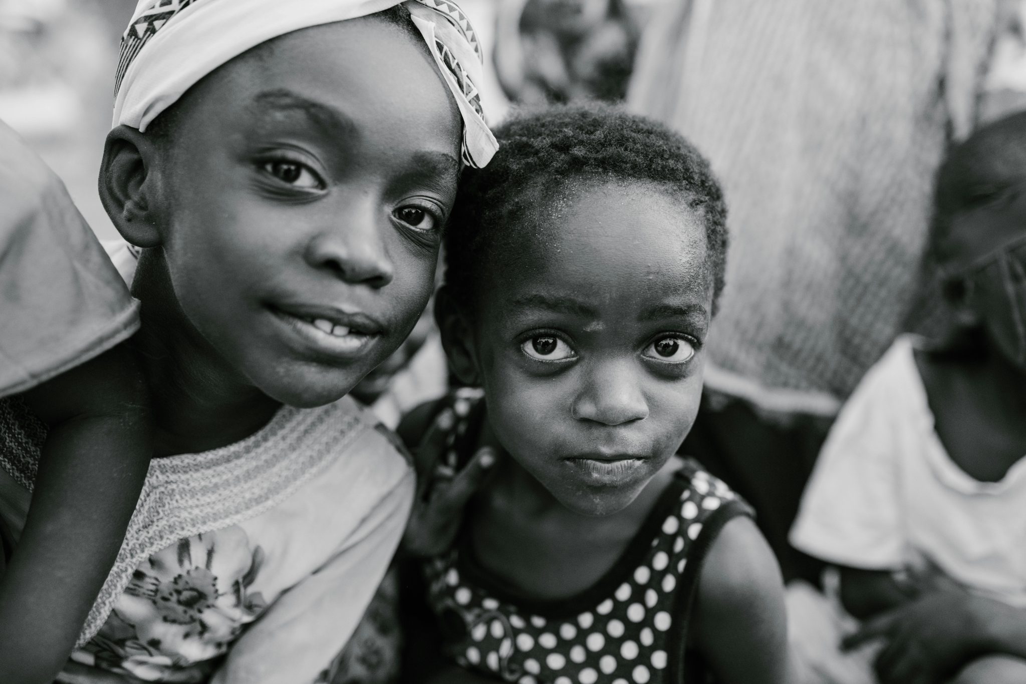 Black and white glad children in casual clothes standing on authentic town street and looking at camera with curiosity